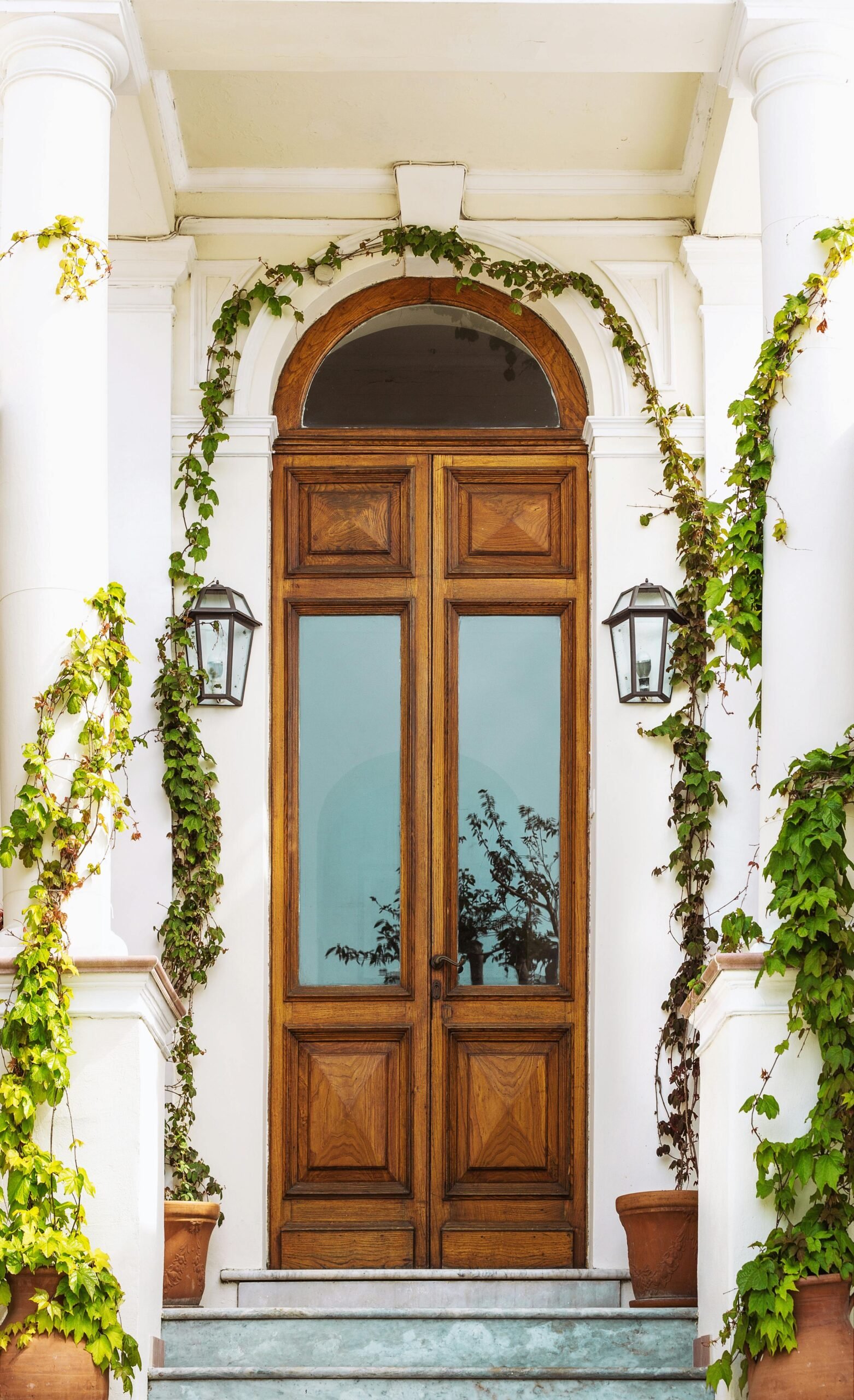 Charming wooden entrance with ivy, potted plants, and vintage lanterns in Capri, Italy.